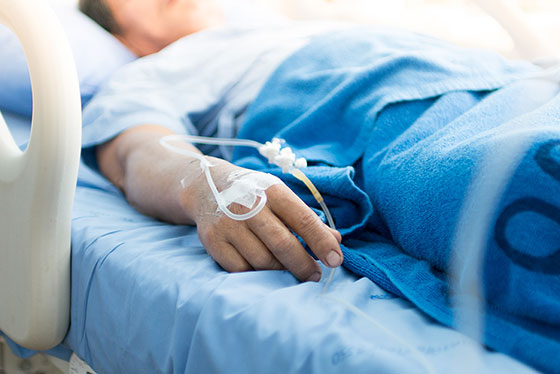 man in a hospital bed with IV in his arm