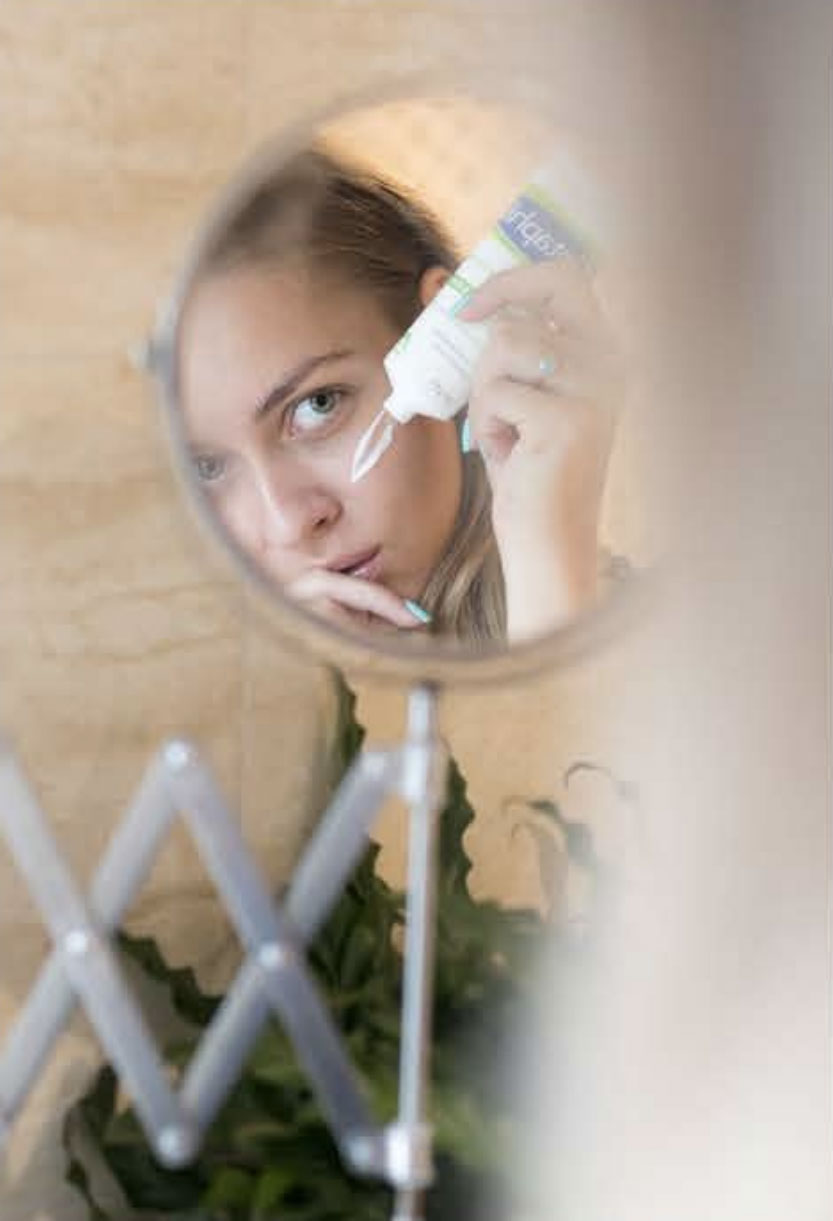 woman doing makeup in mirror